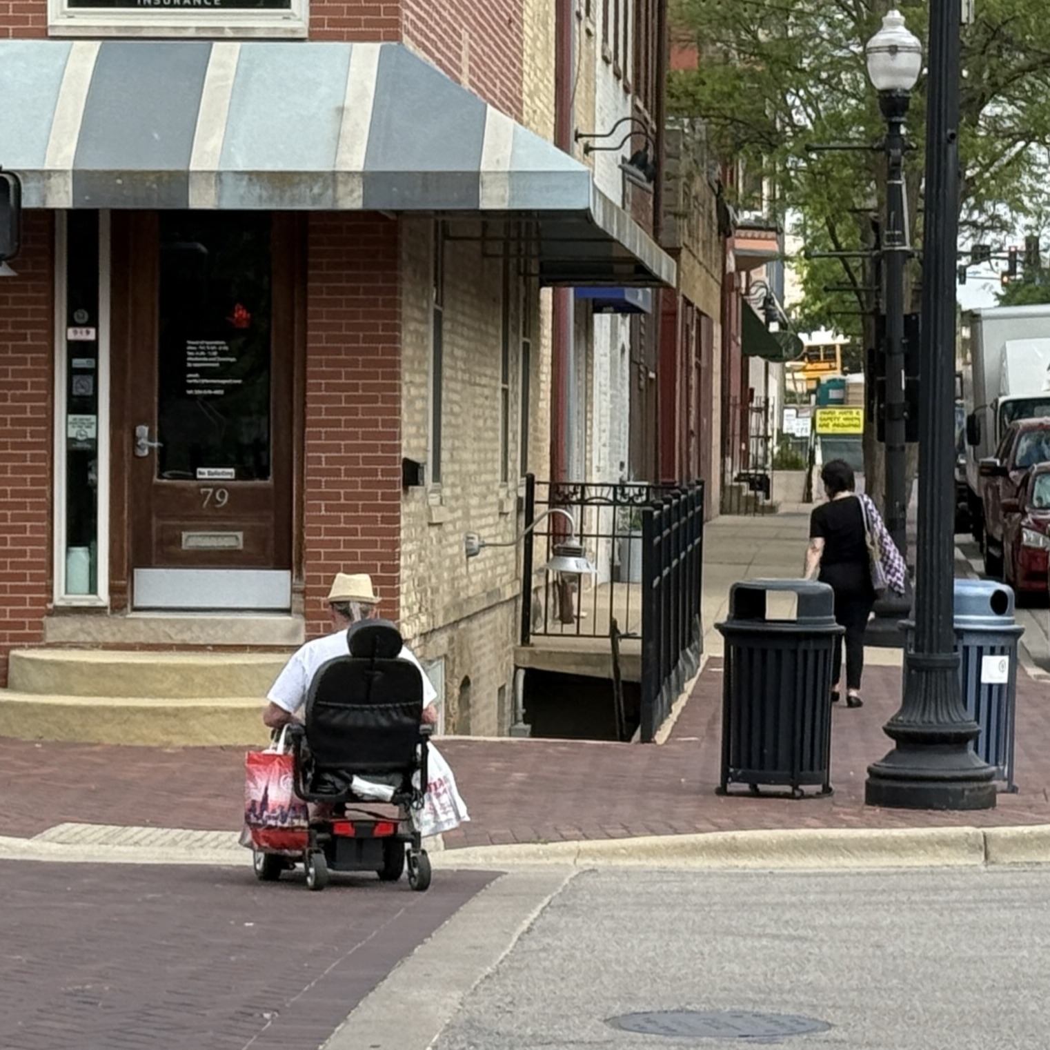 A person in a wheelchair approaching a curb ramp from a crosswalk in downtown Elgin. 